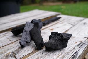 carbón negro sobre fondo de madera vieja, el carbón es esencial para asar a la parrilla. foto