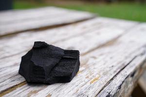 carbón negro sobre fondo de madera vieja, el carbón es esencial para asar a la parrilla. foto