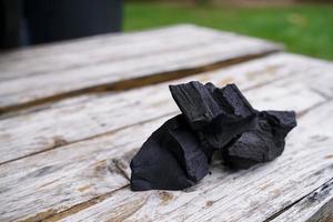 Black charcoal on old wood background, Charcoal is essential in grilling. photo