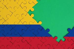 Colombia flag  is depicted on a completed jigsaw puzzle with free green copy space on the right side photo