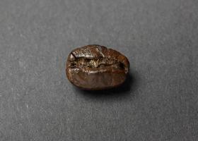 grano de café tostado sobre fondo negro foto