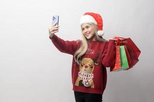 Portrait of happy Caucasian young woman in santa claus hat with  shopping bags over white background photo