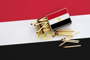 la bandera de egipto se muestra en una caja de cerillas abierta, de la que caen varias cerillas y se encuentra en una gran bandera foto