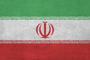 Iran flag depicted in bright paint colors on old relief plastering wall. Textured banner on rough background photo