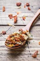 Dried spices, sun-dried tomatoes, dried carrots, Basil and Provencal herbs in a wooden spoon on a wooden table. Copy space.