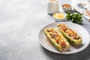 Baked stuffed zucchini boats with minced chicken mushrooms and vegetables with cheese on a plate. Copy space photo