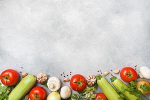 Set of different seasonal vegetables on a gray concrete background. Tomato zucchini onion garlic mushrooms parsley spices. Frame copy space. photo