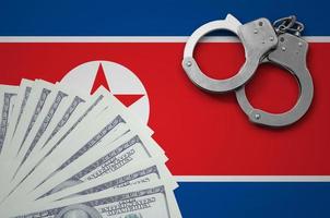 North Korea flag  with handcuffs and a bundle of dollars. The concept of illegal banking operations in US currency photo