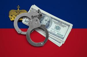 Liechtenstein flag  with handcuffs and a bundle of dollars. Currency corruption in the country. Financial crimes photo