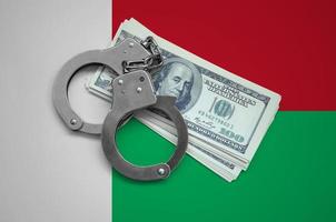 Madagascar flag  with handcuffs and a bundle of dollars. Currency corruption in the country. Financial crimes photo