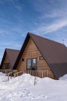 A vertical shot of a wooden cottage surrounded by snow. A recreation area in the mountains photo