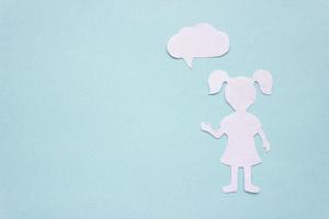 The silhouette of a girl in a dress and with ponytails made of white paper, cut by hand. With speech-bubble in the right side of the photo. With copy space photo