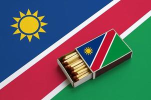 Namibia flag  is shown in an open matchbox, which is filled with matches and lies on a large flag photo