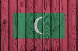 Maldives flag depicted in bright paint colors on old wooden wall. Textured banner on rough background photo