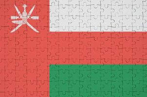 Oman flag  is depicted on a folded puzzle photo