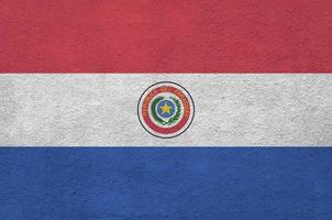 Paraguay flag depicted in bright paint colors on old relief plastering wall. Textured banner on rough background photo