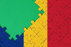 Romania flag  is depicted on a completed jigsaw puzzle with free green copy space on the left side photo