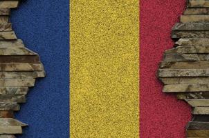 Romania flag depicted in paint colors on old stone wall closeup. Textured banner on rock wall background photo