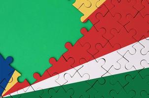 Seychelles flag  is depicted on a completed jigsaw puzzle with free green copy space on the left side photo