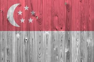 Singapore flag depicted in bright paint colors on old wooden wall. Textured banner on rough background photo