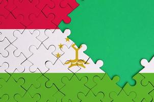 Tajikistan flag  is depicted on a completed jigsaw puzzle with free green copy space on the right side photo