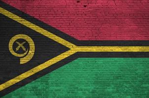 Vanuatu flag depicted in paint colors on old brick wall. Textured banner on big brick wall masonry background photo