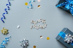 Black friday text with gifts and festive tinsel flat lay photo