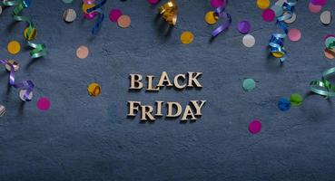 Banner with Black Friday text and holiday tinsel flat lay on dark background. photo