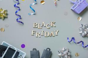 Black friday text with gifts, shopping baskets and festive tinsel flat lay photo