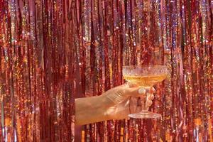 A glass of champagne in a woman's hand on the background of a festive New Year's party background photo