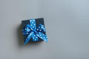 Black gift box with bow flat lay on grey background. View from above. Copy space photo