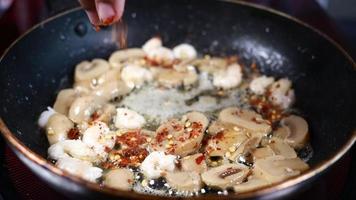 rood Chili vlokken besprenkeld op champignons en garnaal gebakken in boter koekepan video