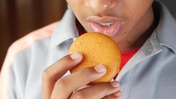 Close up of young man taking a bite out of a muffin pastry video