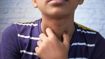 menino toca o pescoço em gesto de dor de garganta video