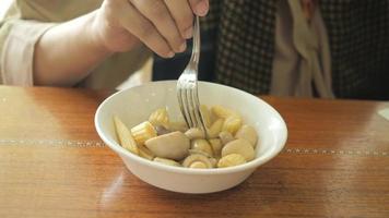 Person eats a bowl of hot mushrooms and baby corn with fork video