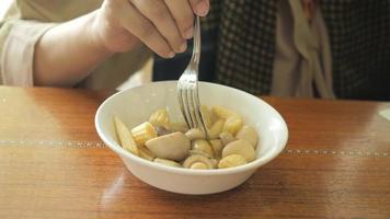 persona mangia un' ciotola di caldo funghi e bambino Mais con forchetta video