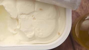 Close up pan of open cream cheese container next to slices of bread video