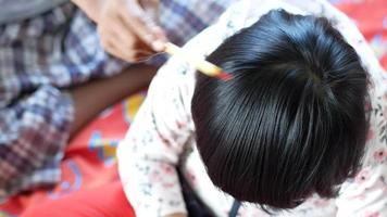 Parent combing shiny black hair of child video
