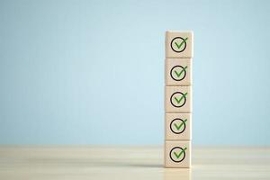 Checklist, Task list, Survey and assessment. Quality Control. Goals achievement and business success. Green check mark icon on wooden blocks. photo