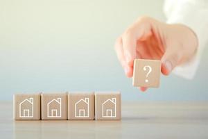 Real estate, Property investment and asset management concept. Hand holding question mark and house on wooden blocks. Decision to choose the best property with your right. Choosing suitable housing. photo