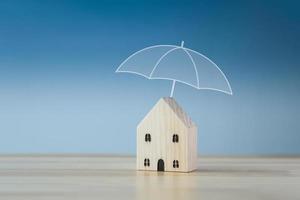 Home insurance. House model with umbrella that protects house. concept for protection to the structure and contents of the house. photo