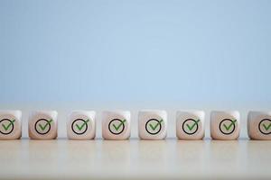 Checklist, Task list, Survey and assessment. Quality Control. Goals achievement and business success. Green check mark icon on wooden blocks. photo