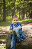 Portrait of a boy in a blue tank top in the woods in spring. Take a walk in the green park in the fresh air. The magical light from the sun's rays falls behind the boy. photo