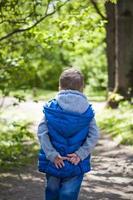 Portrait of a boy in the forest in spring. Take a walk in the green park in the fresh air. The magical light from the sun's rays is left behind. Space for copying. Selective focus. photo