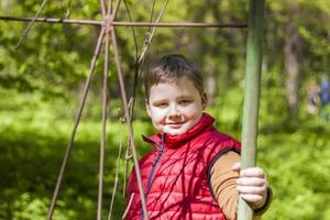 Portrait of a young man in a red tank top in the forest in spring. Walk through the green park in the fresh air. The magical light from the sun's rays falls behind the boy. photo