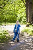 Portrait of a boy in the forest in spring. Take a walk in the green park in the fresh air. The magical light from the sun's rays is left behind. Space for copying. Selective focus. photo