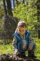 Portrait of a boy in a blue tank top in the woods in spring. Take a walk in the green park in the fresh air. The magical light from the sun's rays falls behind the boy. photo