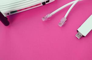 Internet router, portable USB wi-fi adapter and internet cable plugs lie on a bright pink background. Items required for internet photo