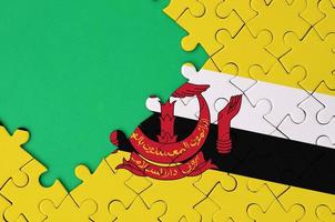 Brunei Darussalam flag  is depicted on a completed jigsaw puzzle with free green copy space on the left side photo