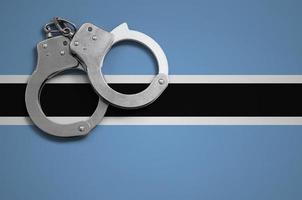 Botswana flag  and police handcuffs. The concept of crime and offenses in the country photo